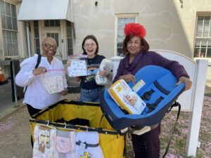 Three ladies hold donated items for babies.